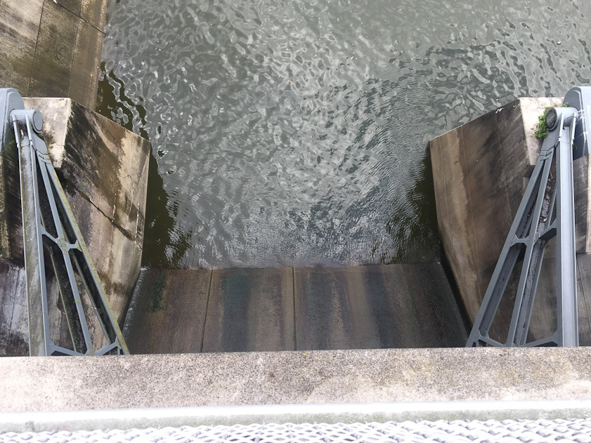 Looking down on the spillway for one gate. The beams on the right and left connect to the gate. Raising and loweing the gate causes these to rotate up and down.