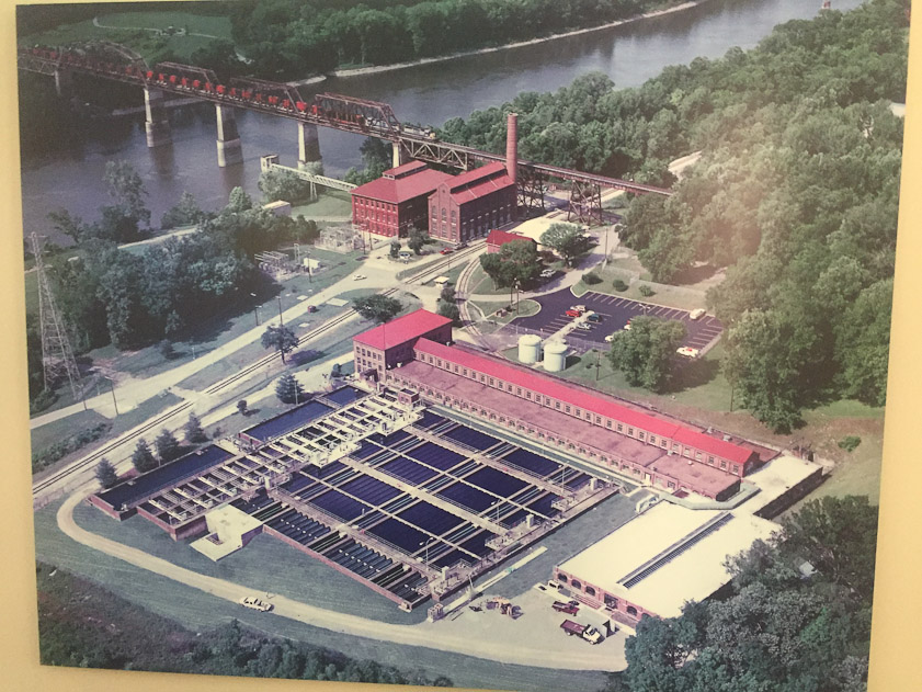 Photo of the Omohundro Water Works of Nashville. The big building near the railway bridge houses the pumps that move water from the inlets in the river to the settling tanks at the bottom center of the photo. The filters are in the long red brick building next to the black settling tanks.