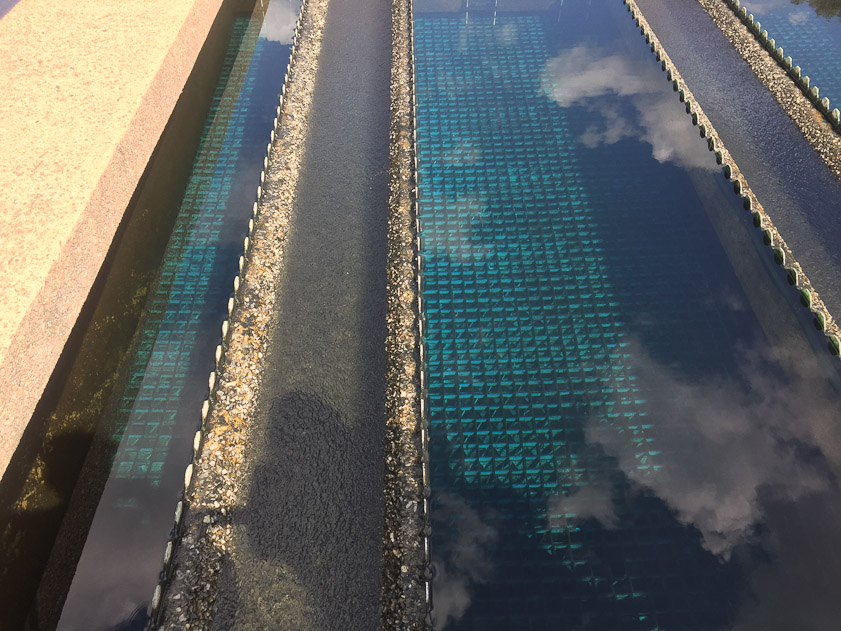 The second set of settling tanks. Floculant is added to aglomerate sediment, which falls to the bottom the slowly flowing water. The photo shows reflections of the clouds in the sky above.