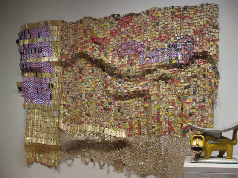 Tapestry made of metal tops of bottles of liquor and cans of evaporated milk, by El Anatsul, Ghanaian, born 1944.