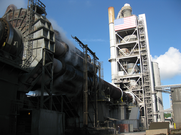 Ash Grove cement plant in Seattle. Blended ingredients (limestone, iron slag, coal ash, and sand) enter at the top of the tower, are mixed and preheated as they descend, and are roasted in the kiln (the horizontal tube leading from the base of the tower toward us. The cement then is divided into nine coolers (the steaming bundle of tubes nearest the camera).