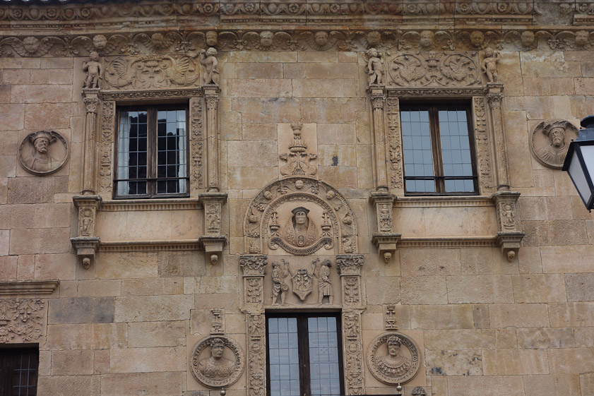 The four skulls are under the pillars framing the windows on the top floor.