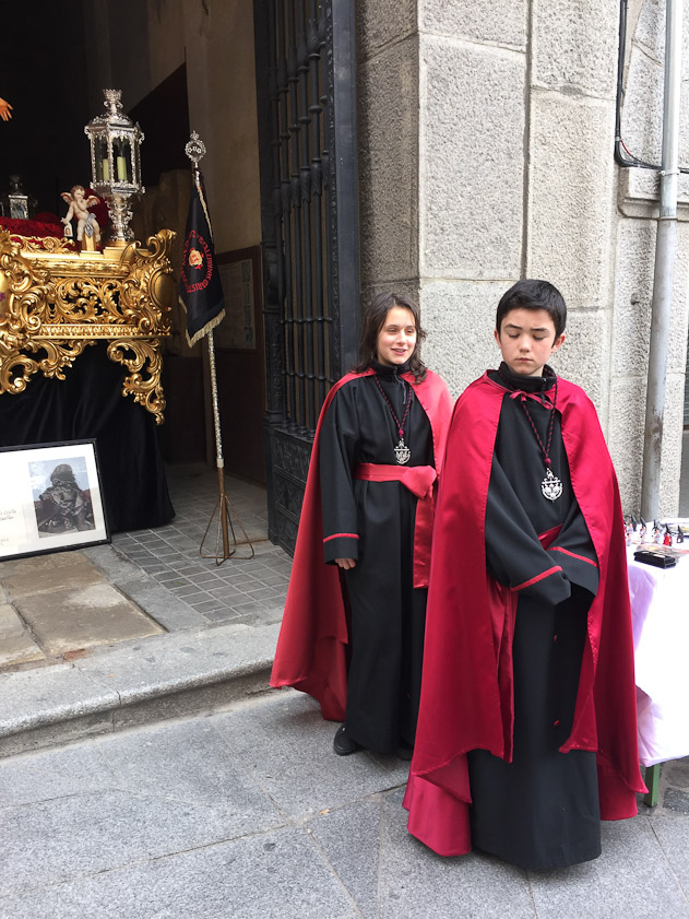 Young members of a confraternity, with their float in its garage behind them, its entrance in a corner of the Plaza Major.
