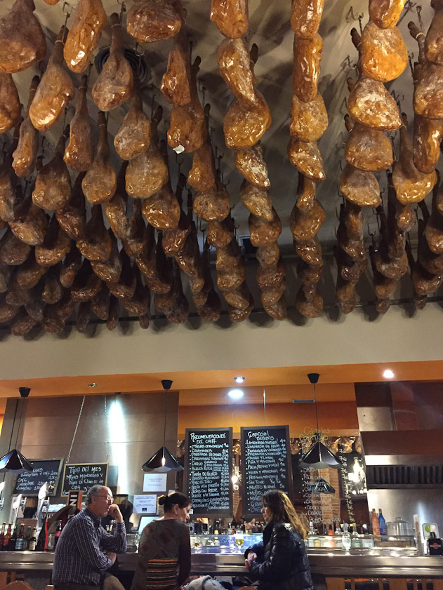 The hams hanging from the ceiling of this bar-restaurant must be fake; that's too much money to tie up in decorations.