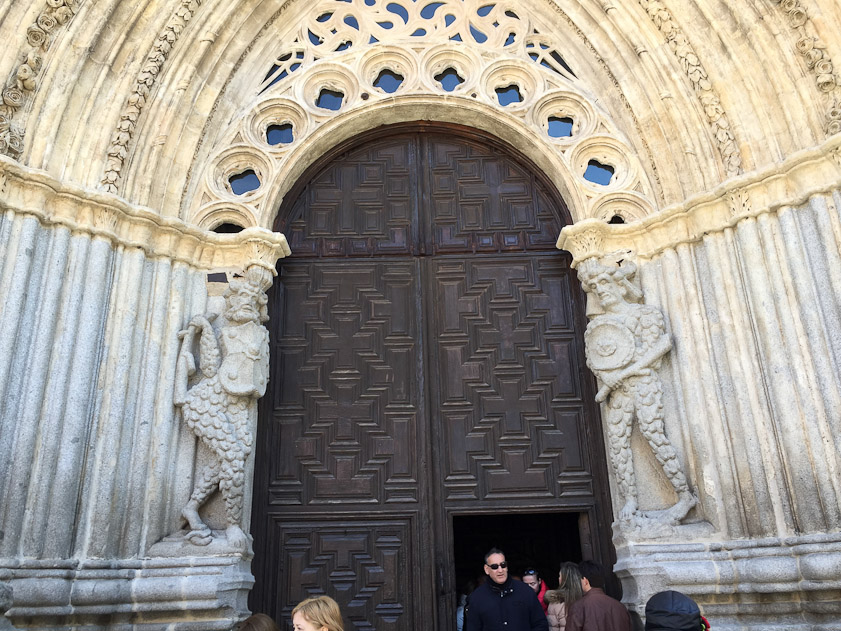 The door is flanked by curious wild men with scaly costumes