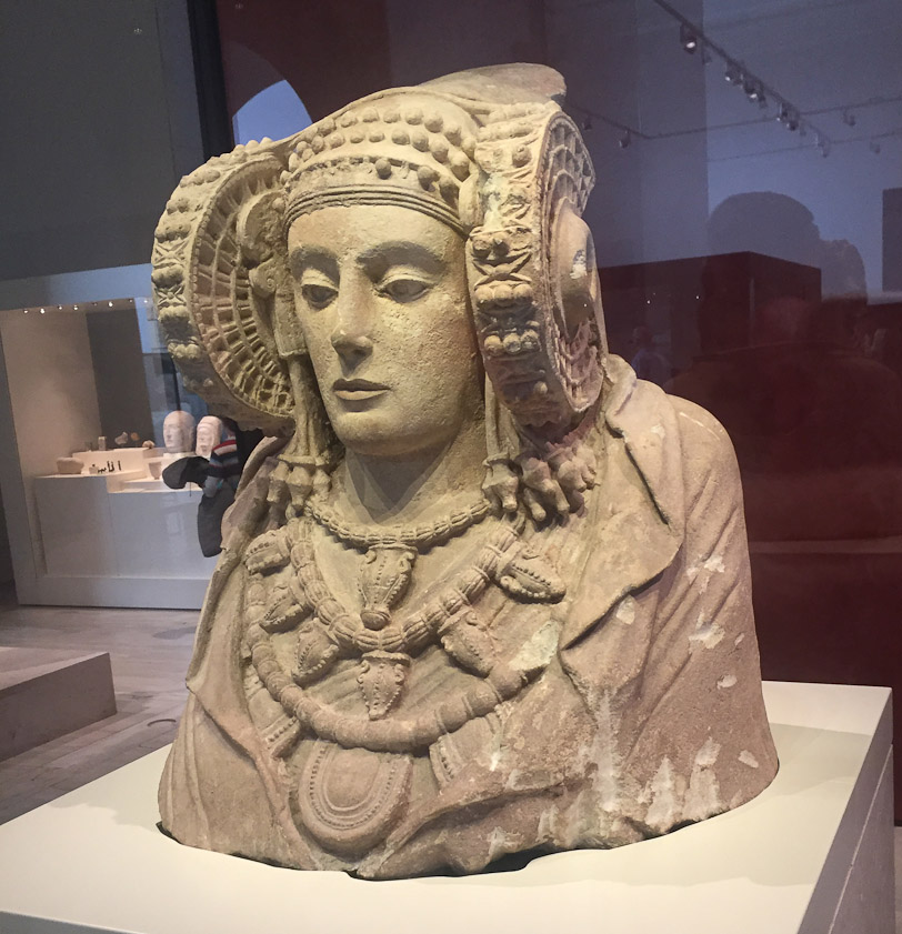 The Dama de Elche (Lady of Elche) was named for the city near where she was found in 1897. She is limestone, from the Iberian culture of 5-4c BC, and was originally painted and had eyes of vitreous paste. The current interpretation is that she was an aristocratic Iberian who was deified by her descendants.