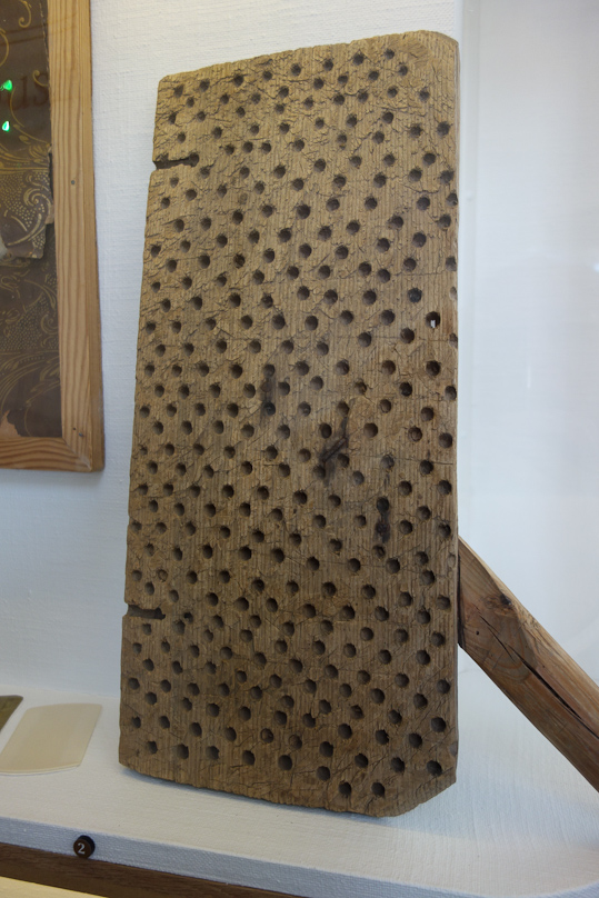 A lice board. You put this under the sheet, and when the lice had sucked their fill and dropped off you they would fall into a hole and be trapped there. In the morning the board was emptied over the fire.