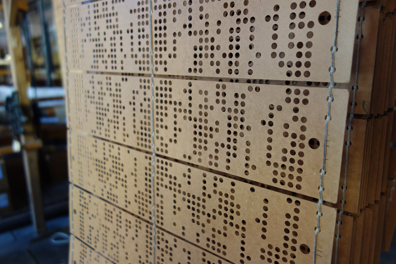 There is one card per thread of the weft. The holes are a matrix 12 high by 50 wide. Each hole presumably controls one headle, through which one warp thread passes. Depending on whether there is a hole or not in the card, the headle is raised or not.