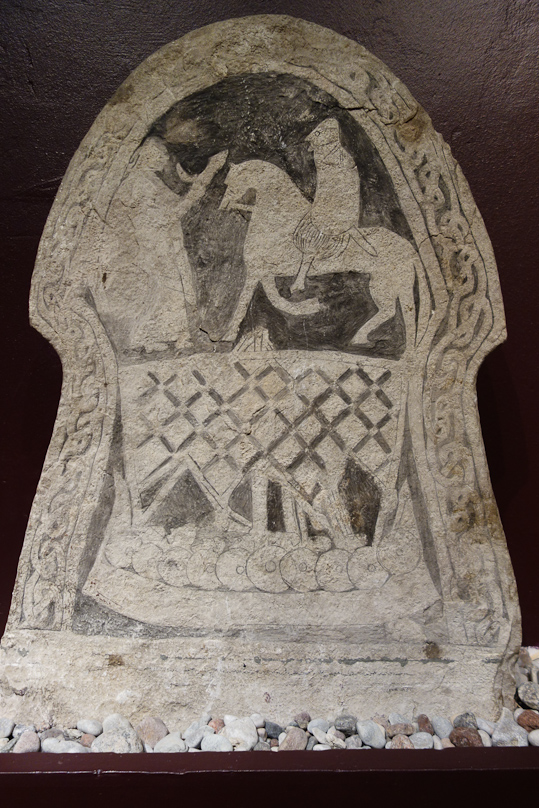 At the bottom, a ship with shields overlapping at the gunwales and a sail criss-crossed with supporting  straps. At the top, a horseback rider and another human. The Gotlands Museum did not offer any interpretation.