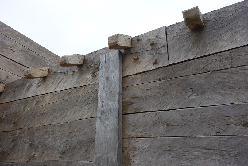 I was impressed by the size of the lumber and the complexity of the joints. The small projecting pieces are the ends of rafters, and the vertical plank covers the junction of the horizontal planks.